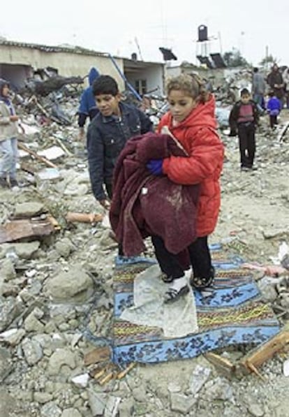 Dos niños palestinos acarrean sus pertenencias, rescatadas de lo que queda de su casa en Rafah.