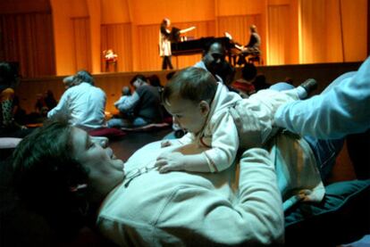 Un padre juega con su bebé en un concierto en Barcelona.