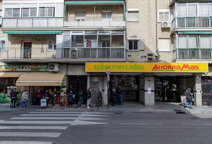 Varias personas con mascarilla hacen cola en un supermercado Ahorra Más a primera hora de la mañana, en Alcorcón.
