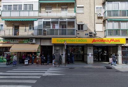 Varias personas con mascarilla hacen cola en un supermercado Ahorra Más a primera hora de la mañana, en Alcorcón.