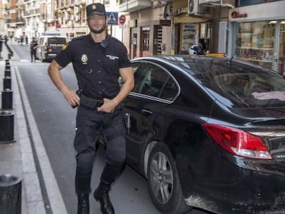 Un membre de la Policia Nacional custodia el vehicle que trasllada dos dels sis policies detinguts a Cartagena.