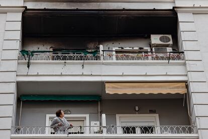 Una mujer observa desde su balcón el piso superior, en el número 51 de la calle Salamanca de València, donde esta madrugada se ha declarado un incendio en el que ha fallecido un hombre y dos mujeres han resultado heridas.