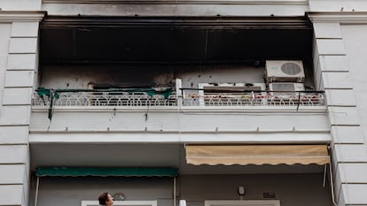 Una mujer observa desde su balcón el piso superior, en el número 51 de la calle Salamanca de València, donde esta madrugada se ha declarado un incendio en el que ha fallecido un hombre y dos mujeres han resultado heridas.