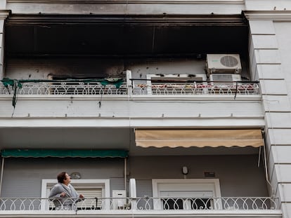 Una mujer observa desde su balcón el piso superior, en el número 51 de la calle Salamanca de València, donde esta madrugada se ha declarado un incendio en el que ha fallecido un hombre y dos mujeres han resultado heridas.