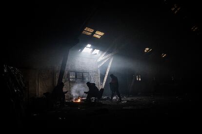 Grupos de refugiados se calientan con hogueras en uno de los almacenes del complejo ferroviario abandonado en el centro de Belgrado (Serbia). 
