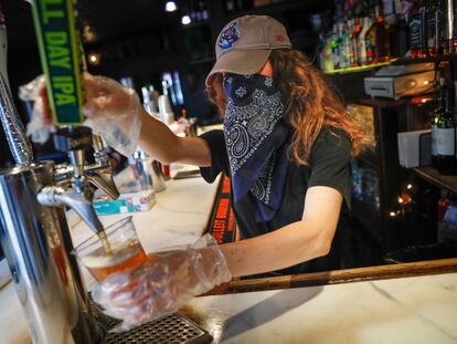 Garçonete serve uma cerveja em um bar de Nova York, em junho.