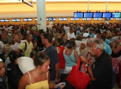 Cientos de turistas esperan ayer en la terminal de salidas del aeropuerto internacional de Cancún.