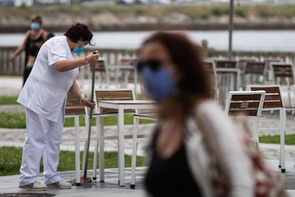 Una trabajadora de un hotel desinfecta la calle donde se encuentra la terraza en el centro de Viveiro, en A Mariña (Lugo).