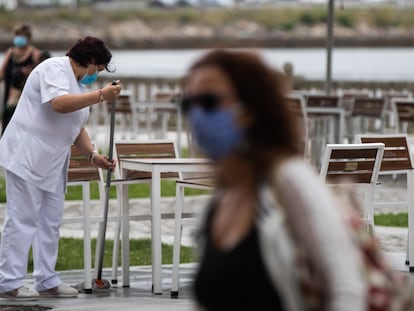 Una trabajadora de un hotel desinfecta la calle donde se encuentra la terraza en el centro de Viveiro, en A Mariña (Lugo).