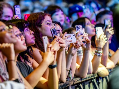 Teenagers use their phones while Alex G performs during a concert in New York.