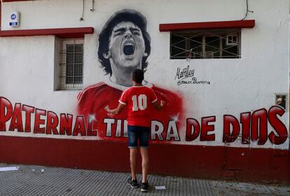 Un aficionado de Argentinos Juniors frente a un mural de Diego Armando Maradona.