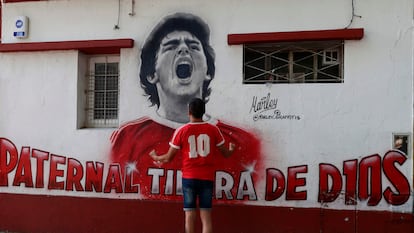 Un aficionado de Argentinos Juniors frente a un mural de Diego Armando Maradona.