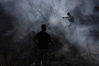 Dos hombres intentan extinguir un incendio forestal en el pueblo de Agia Fotini, cerca de Ierapetra, en la isla de Creta, este jueves.
