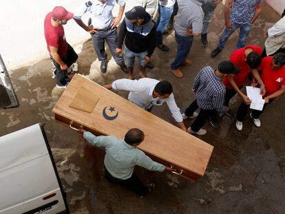 Familiares de un migrante tunecino muerto cargan con su ataúd en la morgue del hospital de Sfax.
