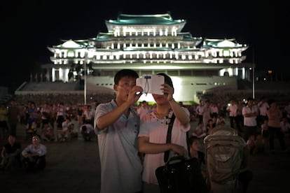 Bajo el régimen de los predecesores de Kim Jong Un, el flujo de información se controlaba principalmente a través de una red humana intensiva en recursos: la 'policía del pensamiento' del Ministerio de Seguridad del Estado, por ejemplo, o los emblemáticos controladores de tráfico de Pyongyang. En la foto, una pareja de norcoreanos utiliza un teléfono inteligente para fotografiar fuegos artificiales en la Plaza Kim Il Sung de Pyongyang, el 27 de julio de 2014.