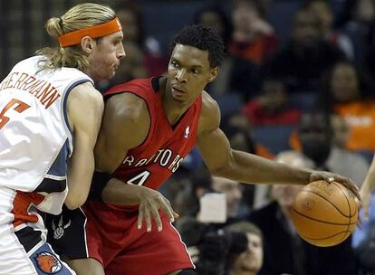 El jugador de los Raptors Chris Bosh (derecha) intenta deshacerse del argentino Walter Herrmann, de los Bobcats.