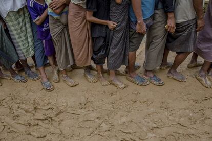 Varios refugiados hacen cola para recoger materiales de construcción para sus albergues, en el campo de refugiados de Kutupalong (Bangladés).