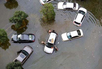 Varias personas empujan un coche atascado en el agua, en una zona de Wuhan, provincia de Hubei, China, el 9 de julio de 2016.