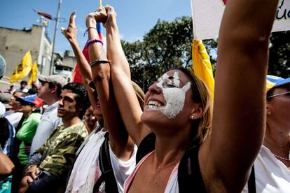 Una mujer con la cara pintada con una mano de blanco, símbolo de la revuelta estudiantil, marcha con otros manifestantes a la Fiscalía General en Caracas.