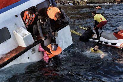 Trabajadores de los servicios de emergencia tratan de ayudar a los refugiados e inmigrantes que este viernes han naufragado frente a la isla griega de Lesbos.