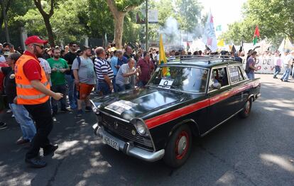 Manifestantes en la huelga de taxis aprecian un coche antiguo que participa en la manifestación de Madrid.