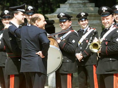 Berlusconi charla con la banda de Carabineros mientras espera la llegada del presidente checo en visita oficial. / EPA