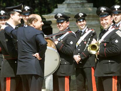 Berlusconi charla con la banda de Carabineros mientras espera la llegada del presidente checo en visita oficial. / EPA