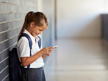 Una colegiala usando su móvil en la escuela.