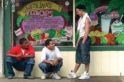 Tres jóvenes, ante el escaparate de un comercio de la calle de Paterson, en Nueva Jersey, que ofrece sus productos en español.