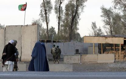 Civiles esperan en la puerta principal del aeropuerto de Kanndahar a que termine el ataque de los talibanes.