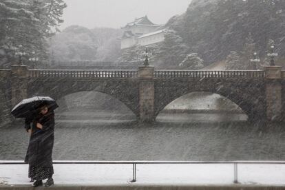 Las fuertes nevadas registradas en Tokio han activado la mayor alerta por este fenómeno meteorológico en cuatro años, además de afectar al tráfico aéreo y ferroviario, así como al transporte por carretera en el centro y norte del país. En la imagen, una mujer se protege con un paraguas mientras pasea delante del Palacio Imperial durante una fuerte nevada en Tokio (Japón), el 22 de enero de 2018.