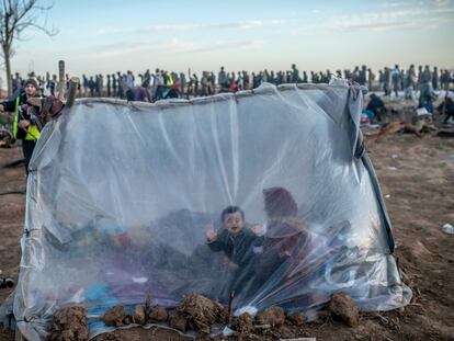 Una mujer siria y sus hijos esperan dentro de su tienda para recibir comida, este martes, en el paso fronterizo de Pazarkule, en Edirne.