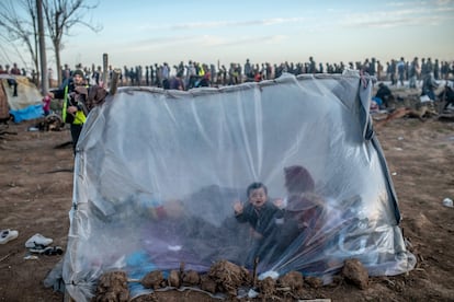 Una mujer siria y sus hijos esperan dentro de su tienda para recibir comida, este martes, en el paso fronterizo de Pazarkule, en Edirne.