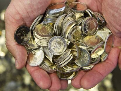 Un hombre sostiene varias monedas de euro. 