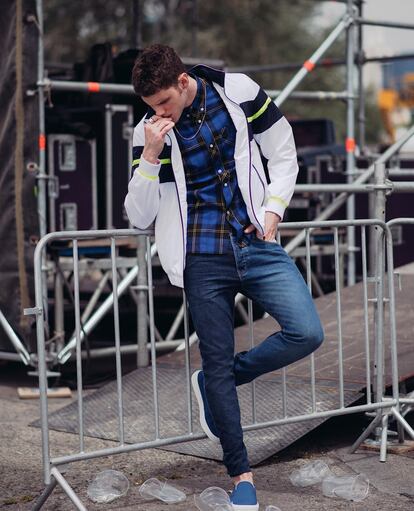 Joan no pierde la esperanza y espera en la valla de encuentro con chaqueta de Lacoste, camiseta de Fred Perry, jeans de Desigual y bisutería vintage. Las zapatillas son de Victoria.