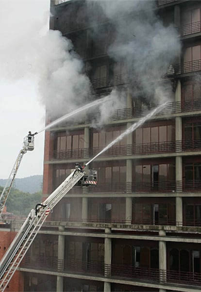 A primera hora, un responsable de Sabico, la empresa de seguridad del edificio, confirmaba el fallecimiento del vigilante y la desaparición de su compañero. Sin embargo, horas después se ha informado de que este guardia tenía que haberse incorcorado al trabajo a las 7.00 y no lo hizo. Además, hubo "alteraciones importantes" en los turnos de los vigilantes "no comunicadas" a la empresa: el fallecido entró a trabajar a las 15.00 de ayer y duplicó su turno. Se desconoce el paradero del vigilante, por lo que está en situación de busca y captura como posible sospechoso. En la foto, varios bomberos atacan el fuego desde una grúa.