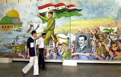 Dos jóvenes iraquíes pasan junto a un mural que representa a Sadam Husein dirigiéndose a conquistar Jerusalén.