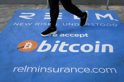 Un hombre camina sobre una alfombra con el logo del bitcoin durante la conferencia sobre la criptomoneda celebrada este mes en Miami.