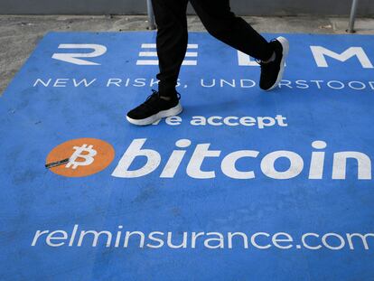 Un hombre camina sobre una alfombra con el logo del bitcoin durante la conferencia sobre la criptomoneda celebrada este mes en Miami.