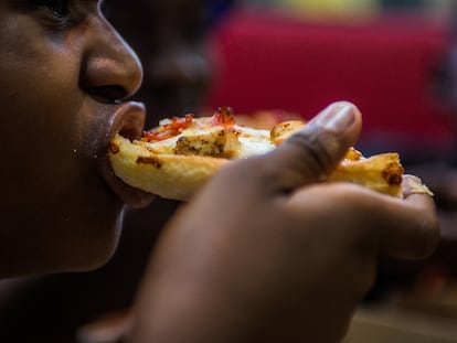 Un joven come un trozo de pizza en un local de comida rápida en Sudáfrica.