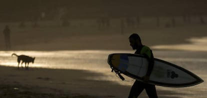 Un surfista sale del agua en la playa de la Zurriola (San Sebastián) al atardecer.