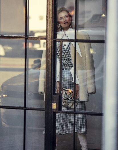 Falda con pechera cruzada de Mulberry, camisa con cuello maxi y apliques de Janashia, abrigo de paño de Chloé, medias de Dim, pendientes de Levens y cartera T-Pouch de la colección cápsula William Morris de Loewe.