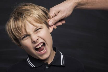 Un padre tira de la oreja a su hijo.