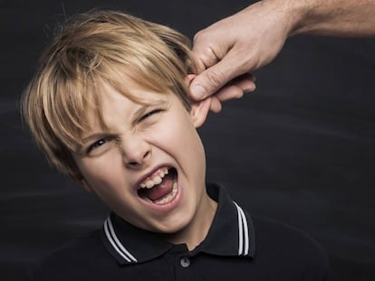 Un padre tira de la oreja a su hijo.