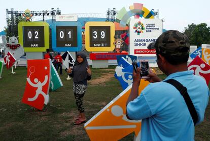 Una chica posa frente al reloj que marca la cuenta atrás para el inicio de los Juegos Asiáticos en la ciudad deportiva de Jakabaring en Palembang (Indonesia). 