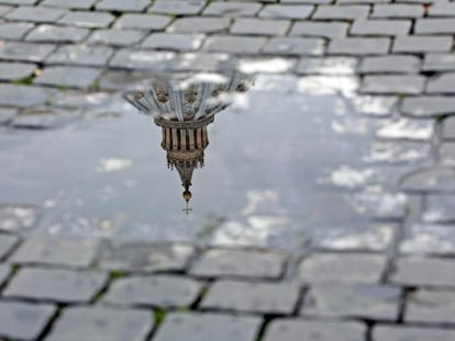 Vista de la cúpula de la basílica de San Pedro reflejada en un charco tras el anuncio de renuncia hecho por el papa Benedicto XVI.