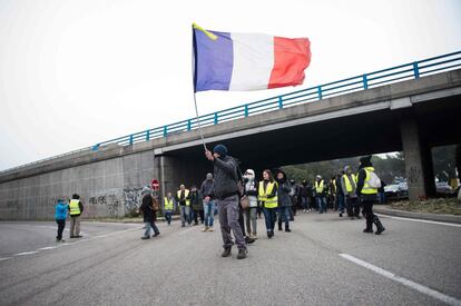 Un hombre sostiene una bandera francesa durante el corte de la autopista A-7 en Sorgues, cerca de Aviñón, durante las protestas de los 'chalecos amarillos'.
