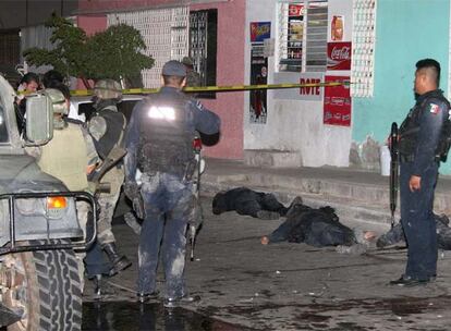 Soldados y policías federales, junto a los cadáveres de tres agentes muertos durante un tiroteo en la ciudad de Culiacán.