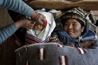 “Zenobia Mamani Ramos descansa en su casa de Patacamaya después de haber dado a luz en una sala con adecuación cultural del hospital de su ciudad. La vemos en la cama junto a su bebé recién nacido y a su madre, la abuela del niño. Es curioso ver a las tres generaciones juntas. Está Zenobia mirando a su hijo con cara de satisfacción y su madre la ayuda arropando al bebé. Esta es una habitación típica de una casa del altiplano boliviano: suelo de madera, camas de madera, un montón de capas de mantas para abrigarse... También están las telas, los gorritos... son prendas que ellos usan porque es propio de su cultura. Esta mujer tenía la suerte de que no necesitaba trabajar, solo iba al mercado a vender cosas, pero después de dar a luz se quedó descansando. Aunque su parto fue muy rápido, después tuvo dolores así que pasó varios días en la cama recuperándose. Fue su madre a ayudarla con el bebé y con las cosas de la casa”.