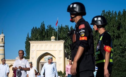 Unos policías chinos vigilan la salida de unos uigures de una mezquita, en 2017 en Kashgar.